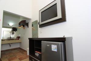 Elle comprend une télévision à écran plat suspendue sur un mur au-dessus d'un réfrigérateur. dans l'établissement Hotel 5 inn, à Silao