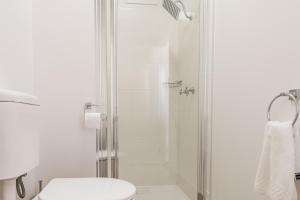 a white bathroom with a shower and a toilet at Somerset Hotel in Somerset