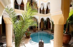 einen Innenhof mit einem Pool in einem Gebäude mit Palmen in der Unterkunft Riad Léna & Spa in Marrakesch