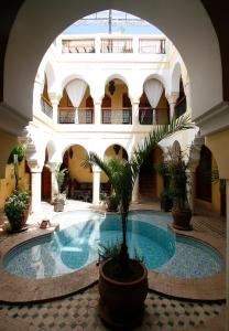 a courtyard with a pool in a building with a palm tree at Riad Léna & Spa in Marrakesh