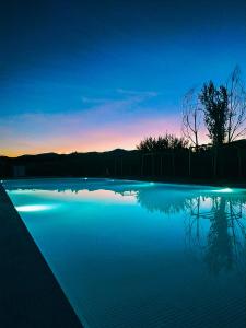 una piscina de agua con una puesta de sol en el fondo en Hotel Bodega El Juncal, en Ronda