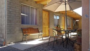 a patio with a table and chairs and an umbrella at Hostal Ckamai in San Pedro de Atacama