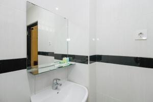 a white bathroom with a sink and a mirror at RedDoorz near Taman Samarendah Samarinda in Samarinda