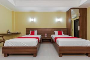 a bedroom with two beds with red pillows at RedDoorz near Taman Samarendah Samarinda in Samarinda