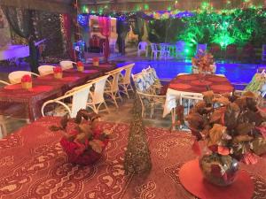 a banquet hall with red tables and vases with flowers at Suítes Veneza in Porto De Galinhas