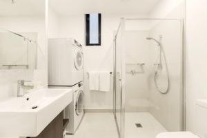 a white bathroom with a shower and a sink at Whitehorse Apartments Hotel in Box Hill