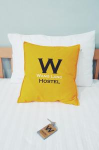 a yellow pillow on a bed with a living long hospital at Wang Lang Hostel in Bangkok