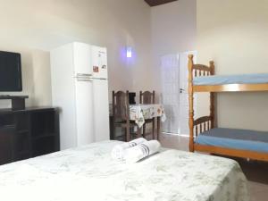 a room with a bed and a refrigerator and a tv at Suítes a Beira Mar in Rio das Ostras