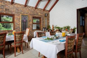 un comedor con mesas y sillas y una pared de ladrillo en Idube Game Reserve en Sabi Sand Game Reserve