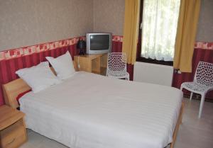 - une chambre avec un grand lit blanc et une télévision dans l'établissement Hotel Beco, à Banneux