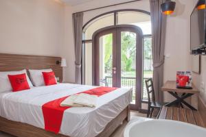een slaapkamer met een groot bed en een balkon bij RedDoorz @ Wiyung 2 in Kedurus