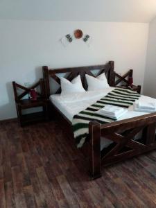 a bedroom with a wooden bed with white sheets at HANUL TENTEA in Săcel