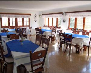 a dining room with blue tables and chairs and windows at Las Verbenas Hotel in La Cumbrecita