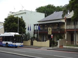 a bus driving down a street next to a building at Manor Boutique Hotel Sydney in Sydney