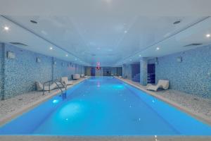 a large swimming pool with blue water in a building at New Peterhof Hotel in Petergof