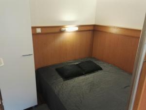 Vuosselin Helmi Apartments في روكا: غرفة نوم صغيرة مع سرير مع وسادة سوداء