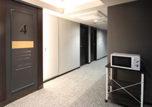 a corridor of an office with a microwave on a cart at Arigato Stay Kanazawa Ekimae in Kanazawa