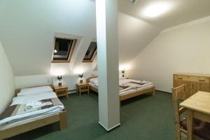 two beds in a room with a table and chairs at Penzion U řízků in Rapotín