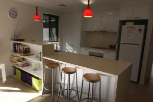 a kitchen with a counter with stools and a refrigerator at 19 Georgian Court in Bright