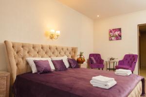 エカテリンブルクにあるотель Вельветのベッドルーム1室(紫色のベッド1台、紫色の椅子2脚付)