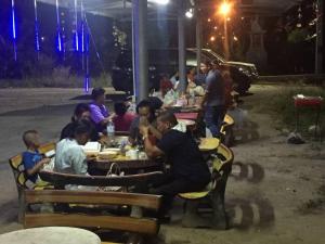 un grupo de personas sentadas en mesas comiendo por la noche en Navy Home Sattahib, en Sattahip