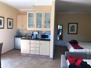 a kitchen with white cabinets and a couch in a room at Wine Cottage by the Sea in Helderberg