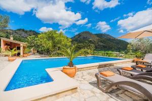 a swimming pool with two chairs and an umbrella at Villa Can Pau By SunVillas Mallorca in Pollença