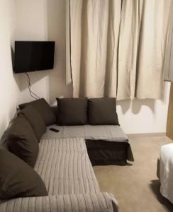un sofá en la sala de estar con TV en la pared en Acetylene B&B en Rapolano Terme