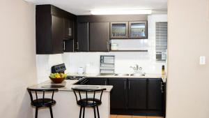 a kitchen with black cabinets and two bar stools at Ezulwini Berg Resort in Ethels Drive
