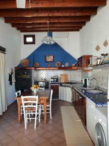 cocina con mesa, sillas y pared azul en Villa Amanda, en Mazara del Vallo
