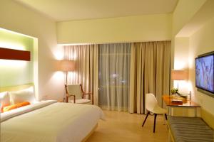 HARRIS Hotel & Conventions Bekasi في بيكاسي: غرفه فندقيه سرير كبير وتلفزيون