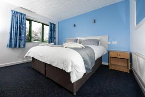 a blue bedroom with a large bed and a window at National Badminton Centre Lodge & Health Club in Milton Keynes