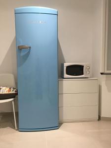 a blue refrigerator in a kitchen with a microwave at 2 rue Palmaro à côté de la plage in Menton