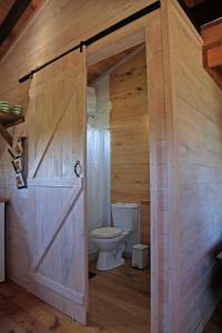 a bathroom with a toilet and a wooden door at Bien de Bien in Punta Del Diablo