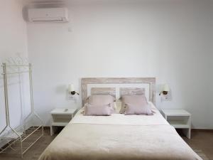 una camera bianca con un grande letto con cuscini rosa di El Manantial B&B a El Higuerón