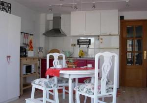 cocina con mesa roja y 2 sillas blancas en Calablu, en Alicante