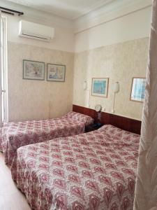 a hotel room with two beds and two lamps at Hotel Cronstadt in Nice