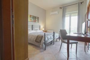 a bedroom with a bed and a desk and a table and chair at Cannatello home - Affittacamere in Villaggio Mosè