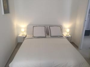 a white bed with two pillows on top of it at 2 rue Palmaro à côté de la plage in Menton