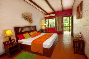 ein Schlafzimmer mit einem Bett mit orangefarbenen und gelben Kissen in der Unterkunft Pachira Lodge in Tortuguero