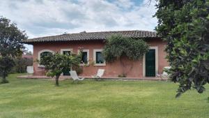 una pequeña casa roja con sillas en un patio en Tenuta San Calogero Appartamento Alloro, en Agnone Bagni
