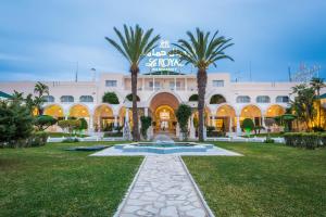 un grand bâtiment avec des palmiers devant lui dans l'établissement Le Royal Hammamet, à Hammamet