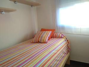 Dormitorio pequeño con cama y ventana en Apartamentos Deluxe Playa Norte, en Peñíscola