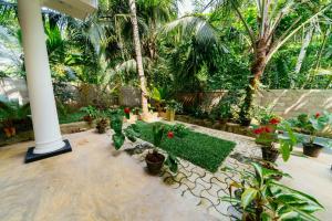 a garden with palm trees and plants and a white pole at Shirani nature palace Midigama in Weligama