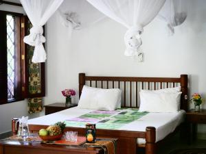 a bedroom with a bed with white curtains and a table at Diani Cottages in Diani Beach