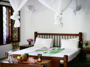 1 dormitorio con 1 cama con cortinas blancas y mesa en Diani Cottages en Diani Beach