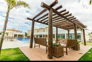 a wooden pergola with benches on a patio at Terra de Gabriela e Jorge Amado,Todo refrigerado! in Ilhéus