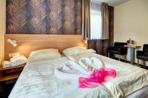 a bedroom with a bed with a pink dress on it at Hotel Helios in Lipova Lazne