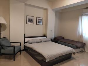 sypialnia z 2 łóżkami pojedynczymi i krzesłem w obiekcie Taichung HSR Homestay w mieście Wuri