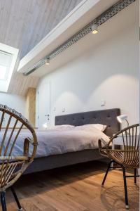 een slaapkamer met een groot bed en 2 stoelen bij b room in Brugge